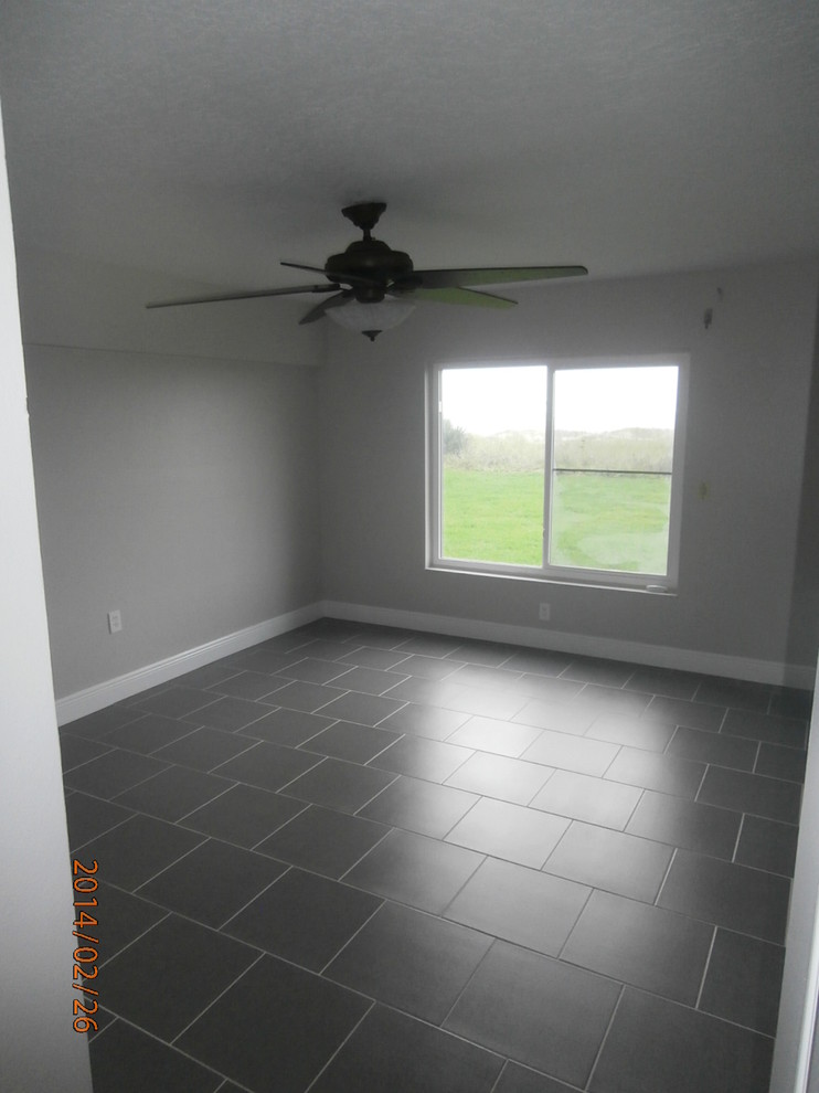 Foto de dormitorio principal costero de tamaño medio con paredes grises y suelo de baldosas de porcelana