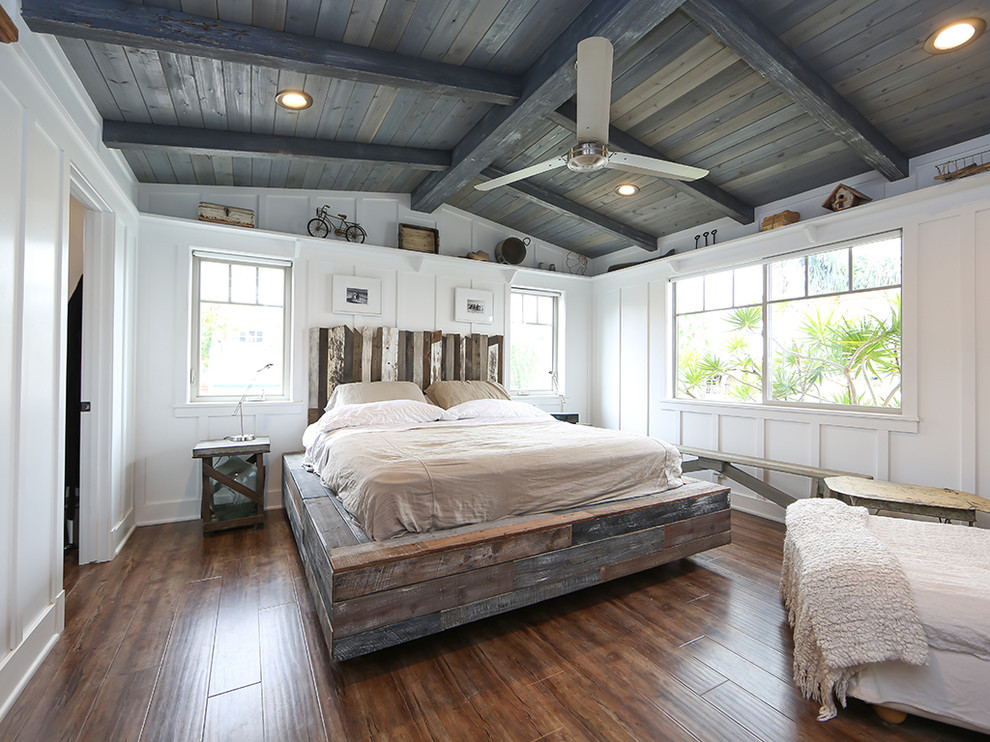 This is an example of a rural master bedroom in Orange County with white walls and medium hardwood flooring.