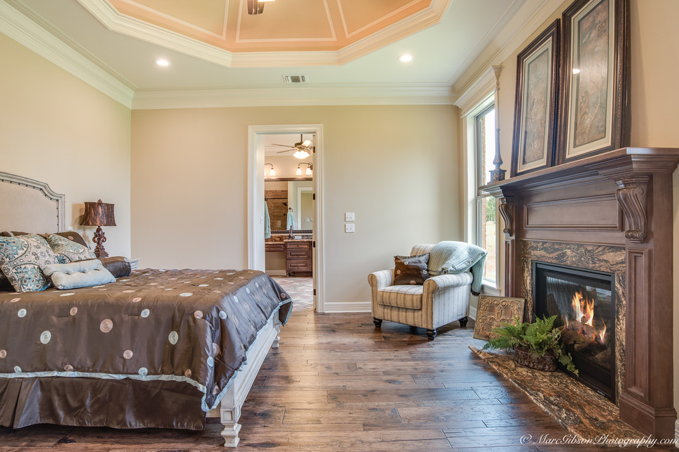 Cette image montre une chambre parentale rustique de taille moyenne avec un mur beige, un sol en bois brun, une cheminée standard et un manteau de cheminée en carrelage.