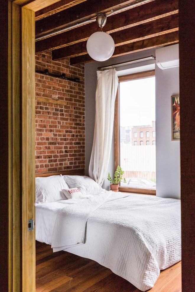 Foto di una camera da letto industriale con pareti bianche, pavimento in legno massello medio e pavimento marrone