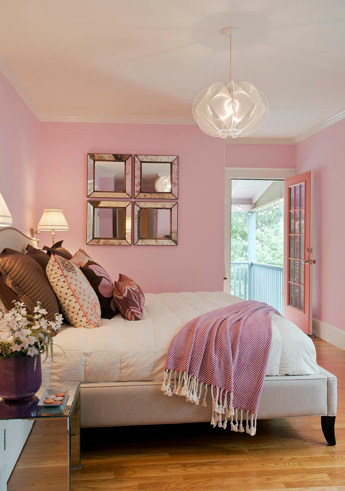 This is an example of a medium sized eclectic master bedroom in Boston with pink walls and light hardwood flooring.