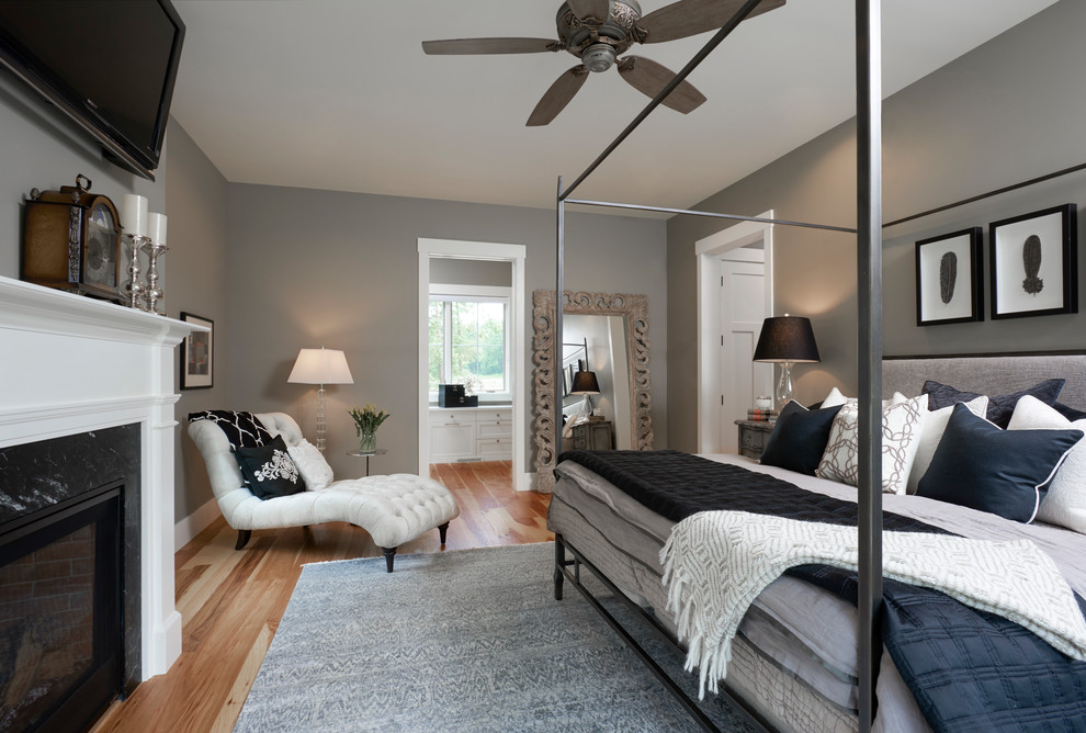 Photo of a medium sized traditional master and grey and brown bedroom in Detroit with grey walls, medium hardwood flooring, a standard fireplace, brown floors and a stone fireplace surround.