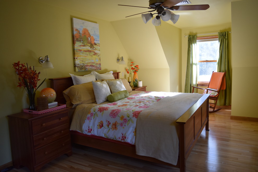 Diseño de dormitorio principal tradicional renovado de tamaño medio sin chimenea con paredes amarillas y suelo de madera clara