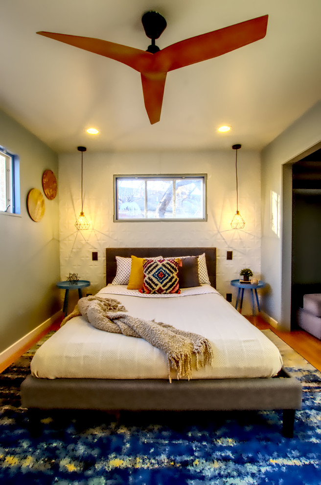 Cette image montre une chambre d'amis design de taille moyenne avec un mur gris, un sol en bois brun, aucune cheminée et un sol marron.