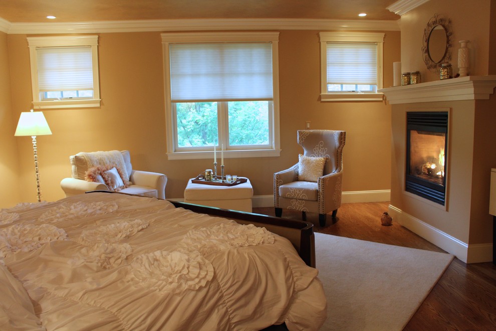 Example of a large eclectic master medium tone wood floor bedroom design in Boston with yellow walls, a standard fireplace and a plaster fireplace