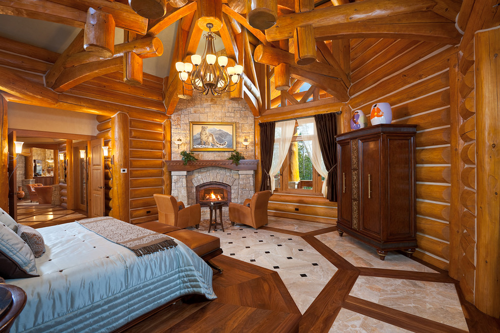 Ejemplo de dormitorio principal rural con paredes marrones, suelo de madera en tonos medios, todas las chimeneas, marco de chimenea de piedra y suelo marrón