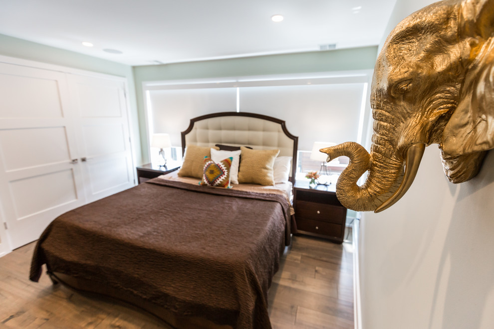 Ejemplo de habitación de invitados ecléctica de tamaño medio con paredes verdes, suelo de madera en tonos medios y suelo marrón