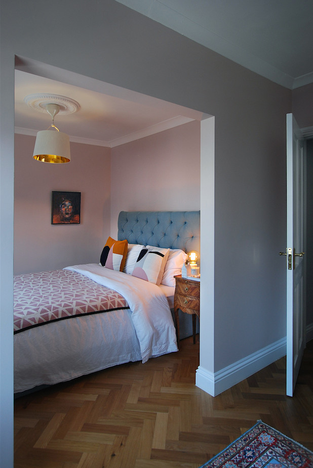 Exemple d'une petite chambre d'amis grise et rose moderne avec un mur rose, un sol en bois brun, aucune cheminée et un sol marron.