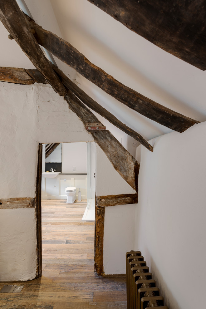 Imagen de habitación de invitados tradicional pequeña con paredes blancas, suelo de madera en tonos medios y suelo marrón