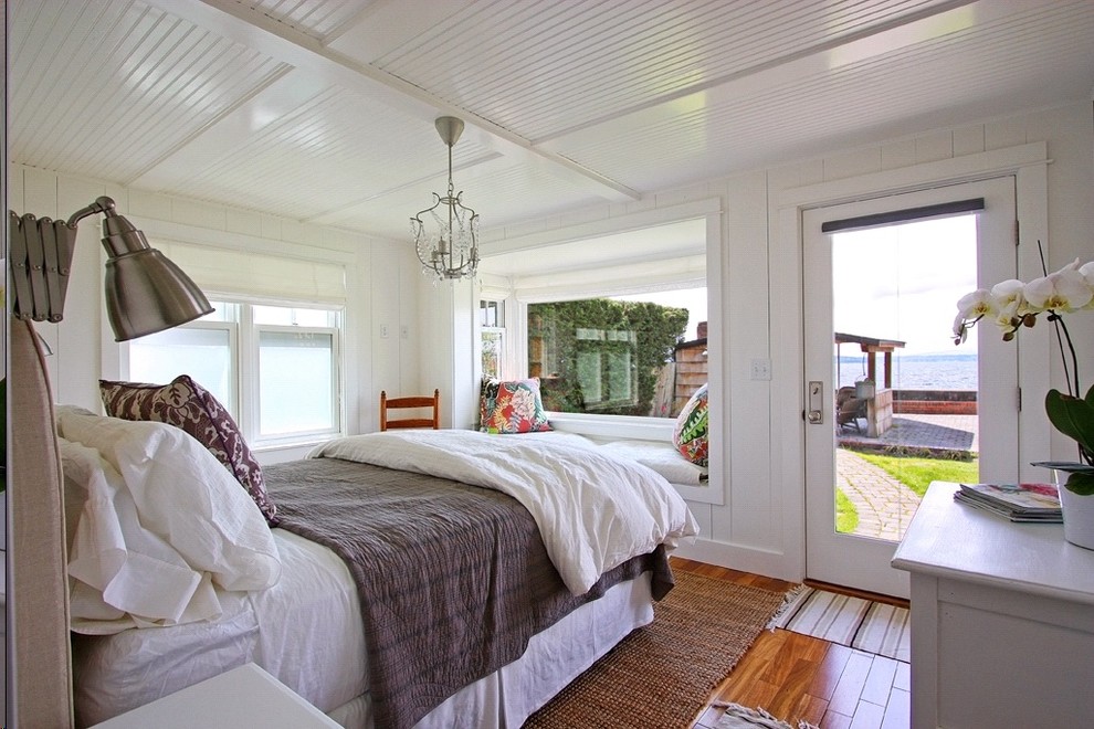Example of a beach style medium tone wood floor bedroom design in Seattle with white walls