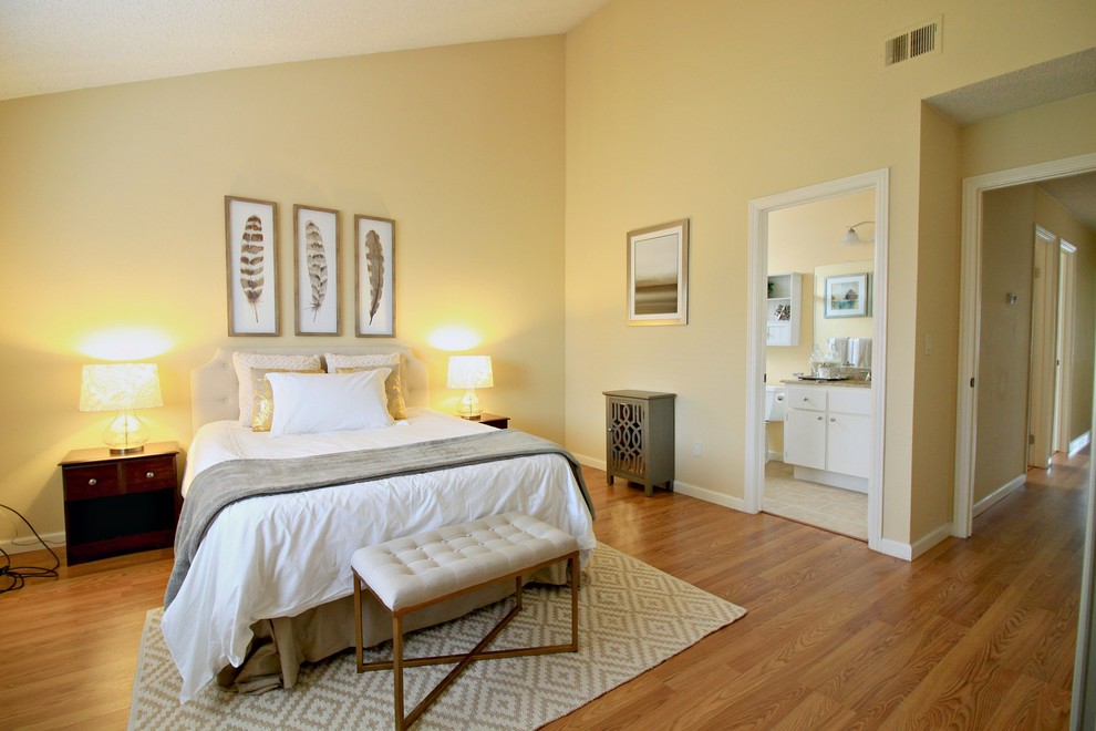 Modelo de dormitorio principal contemporáneo de tamaño medio con paredes amarillas y suelo de madera en tonos medios