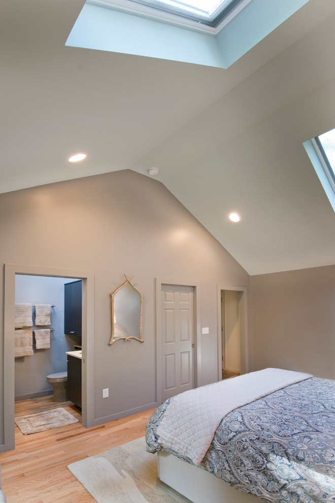 Modelo de dormitorio principal actual de tamaño medio sin chimenea con paredes grises y suelo de madera clara