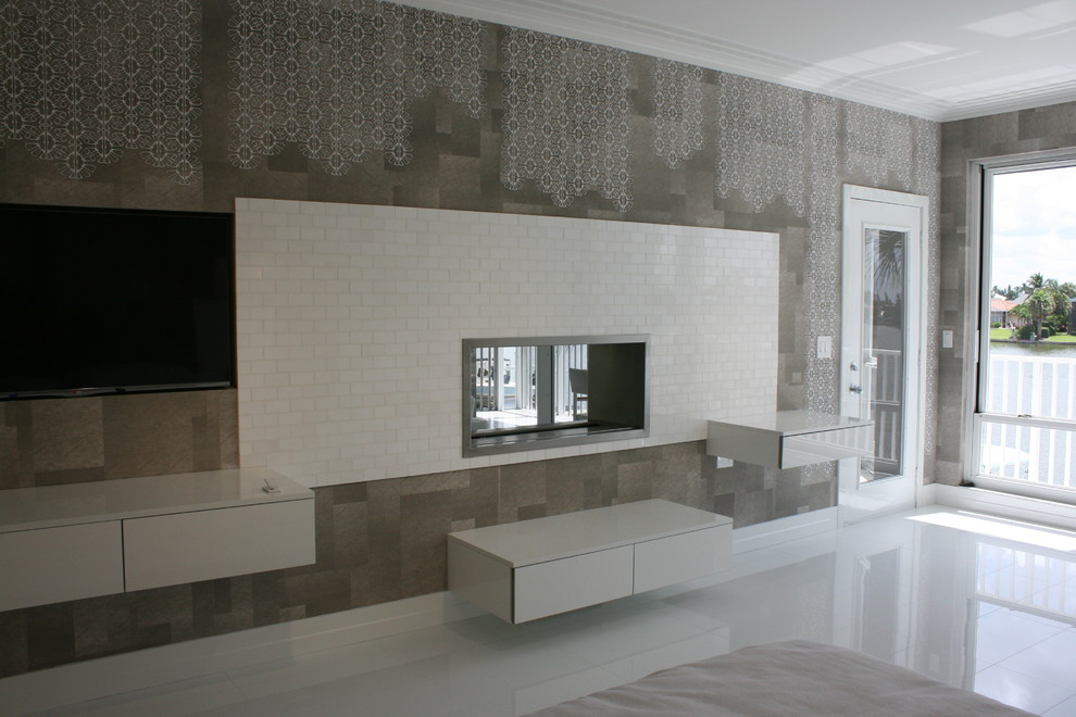 Пример оригинального дизайна: большая хозяйская спальня в современном стиле с серыми стенами, мраморным полом, двусторонним камином и фасадом камина из плитки