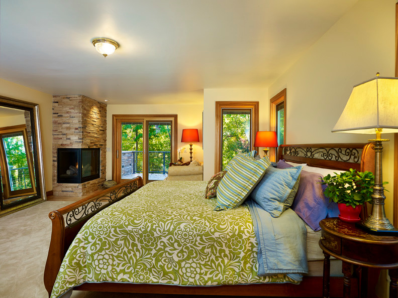 Foto de dormitorio principal de estilo americano grande con paredes beige, moqueta, chimenea de esquina y marco de chimenea de piedra