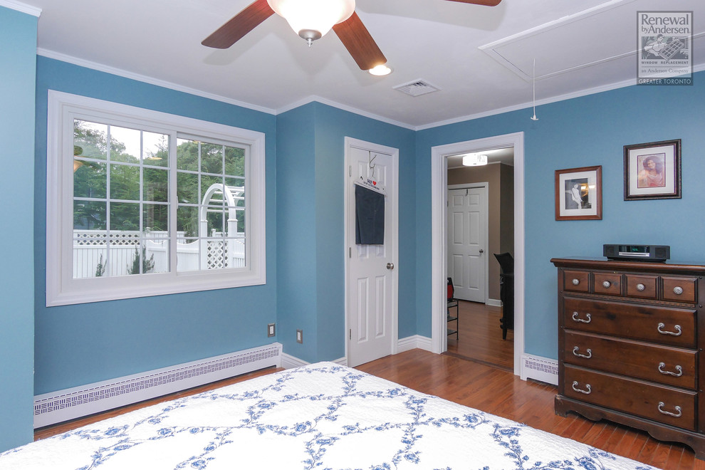 Idée de décoration pour une chambre parentale tradition de taille moyenne avec un mur bleu, un sol en bois brun et aucune cheminée.