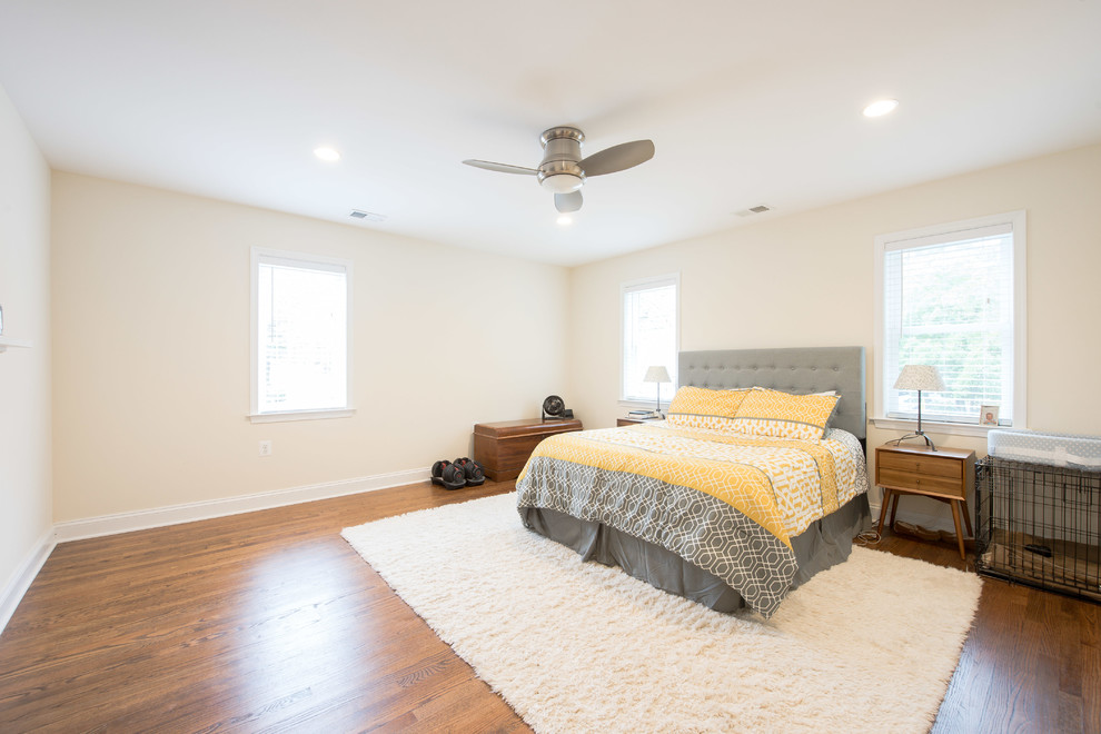 Exemple d'une chambre parentale rétro de taille moyenne avec un mur beige, un sol en bois brun, un sol marron, une cheminée standard et un manteau de cheminée en plâtre.