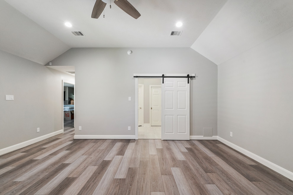 ヒューストンにある中くらいなコンテンポラリースタイルのおしゃれな主寝室 (グレーの壁、ラミネートの床、暖炉なし、茶色い床、格子天井) のインテリア