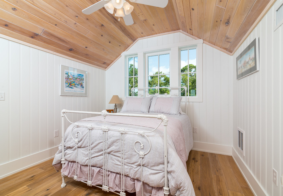 Ejemplo de dormitorio tipo loft marinero de tamaño medio con paredes blancas y suelo de madera en tonos medios