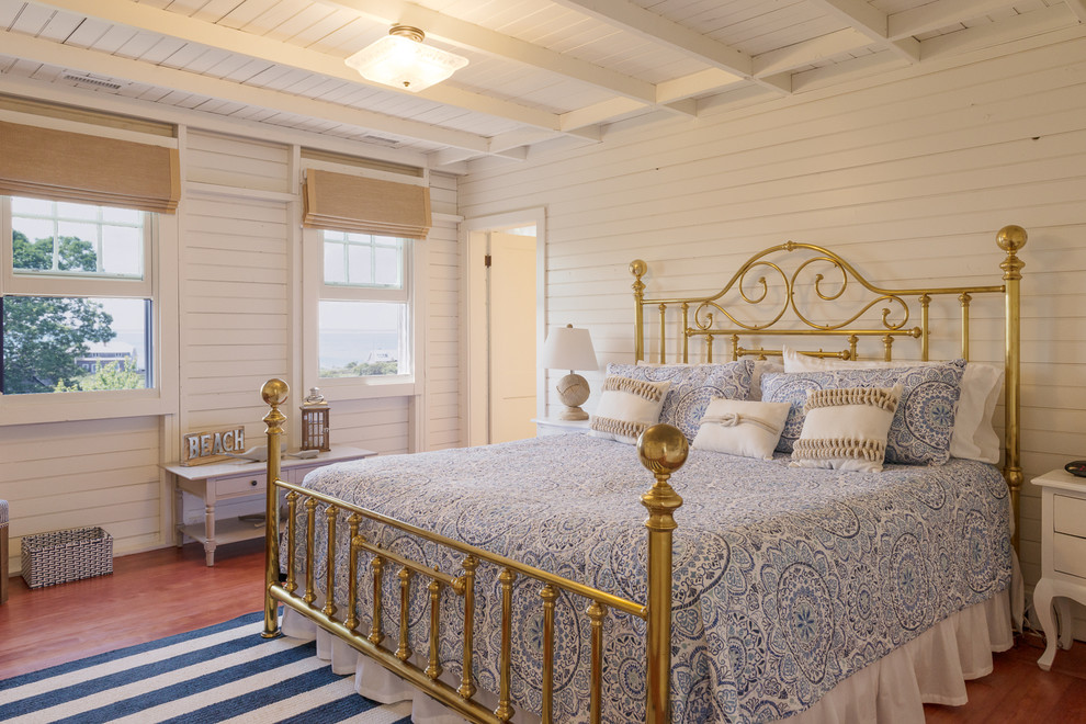 Diseño de dormitorio principal marinero de tamaño medio con paredes blancas y suelo de madera en tonos medios