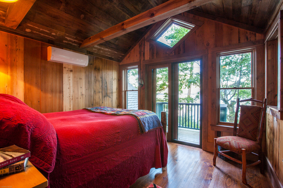 Ejemplo de dormitorio principal rural de tamaño medio sin chimenea con paredes marrones y suelo de madera en tonos medios