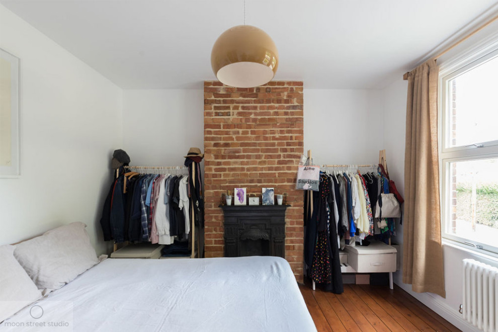 ロンドンにある中くらいなコンテンポラリースタイルのおしゃれな主寝室 (白い壁、無垢フローリング、標準型暖炉、金属の暖炉まわり、茶色い床) のレイアウト