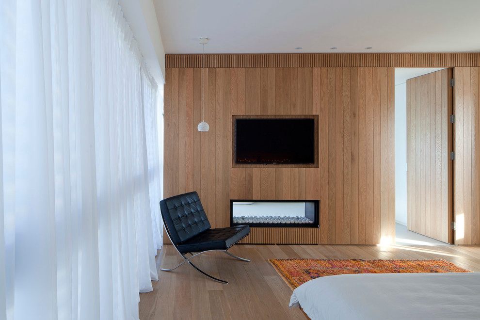 На фото: спальня в современном стиле с двусторонним камином с