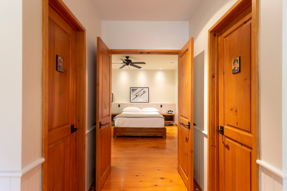 モントリオールにある広いラスティックスタイルのおしゃれな主寝室 (白い壁、無垢フローリング、暖炉なし、オレンジの床)