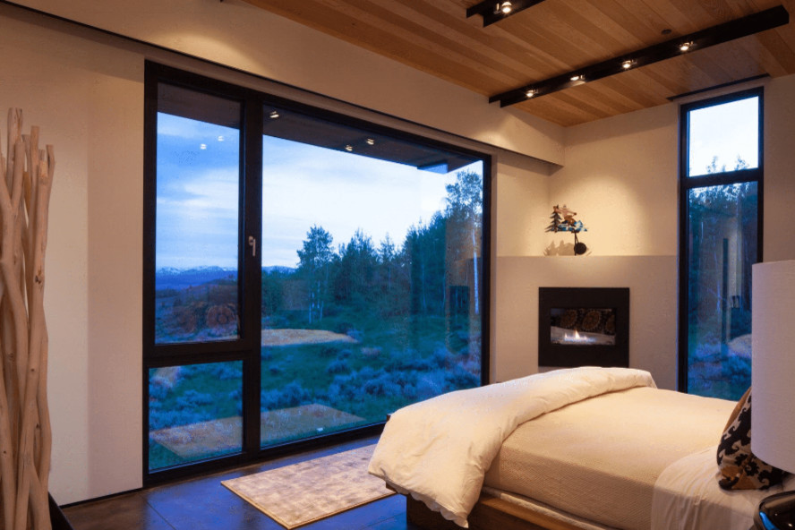 Mittelgroßes Modernes Schlafzimmer mit beiger Wandfarbe, Betonboden, Eckkamin, verputzter Kaminumrandung und braunem Boden in Sonstige