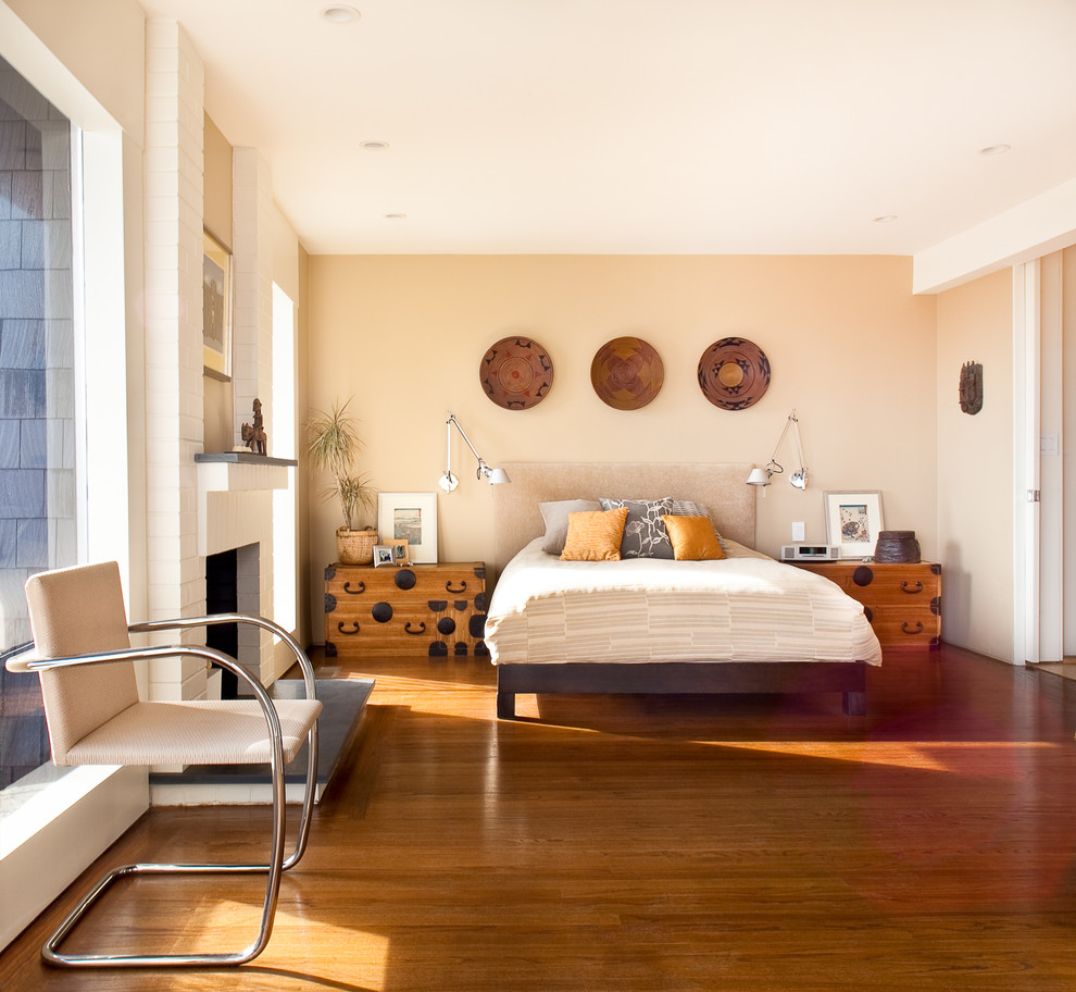 Imagen de dormitorio contemporáneo sin chimenea con paredes beige y suelo de madera en tonos medios