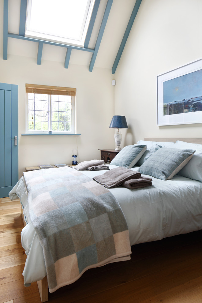 Modelo de habitación de invitados de estilo de casa de campo de tamaño medio sin chimenea con paredes beige, suelo de madera en tonos medios y suelo marrón