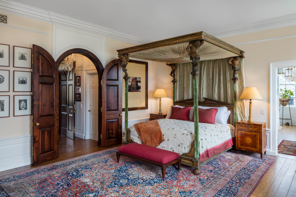 Klassisches Schlafzimmer mit beiger Wandfarbe, dunklem Holzboden, braunem Boden und vertäfelten Wänden in Bridgeport