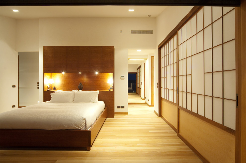 Modelo de dormitorio principal de estilo zen con paredes blancas, suelo de madera clara y suelo beige