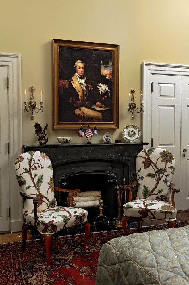 Mittelgroßes Klassisches Gästezimmer mit gelber Wandfarbe, braunem Holzboden, Kaminumrandung aus Stein, Kamin und braunem Boden in Washington, D.C.