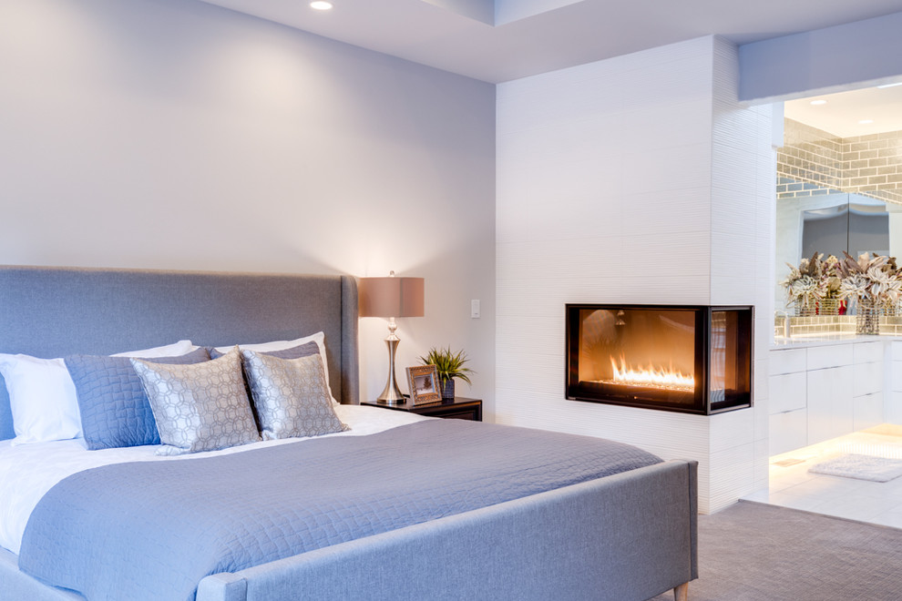Стильный дизайн: хозяйская спальня среднего размера в стиле модернизм с белыми стенами, ковровым покрытием, угловым камином, фасадом камина из плитки и серым полом - последний тренд