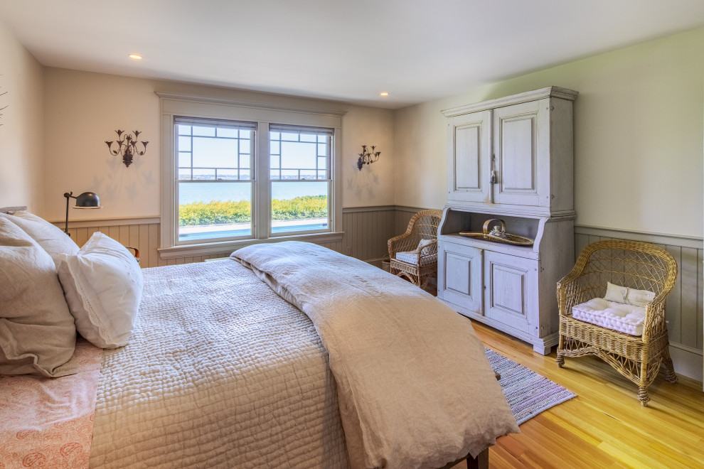 Immagine di una camera da letto stile marinaro con pareti beige, pavimento in legno massello medio, pavimento marrone e boiserie