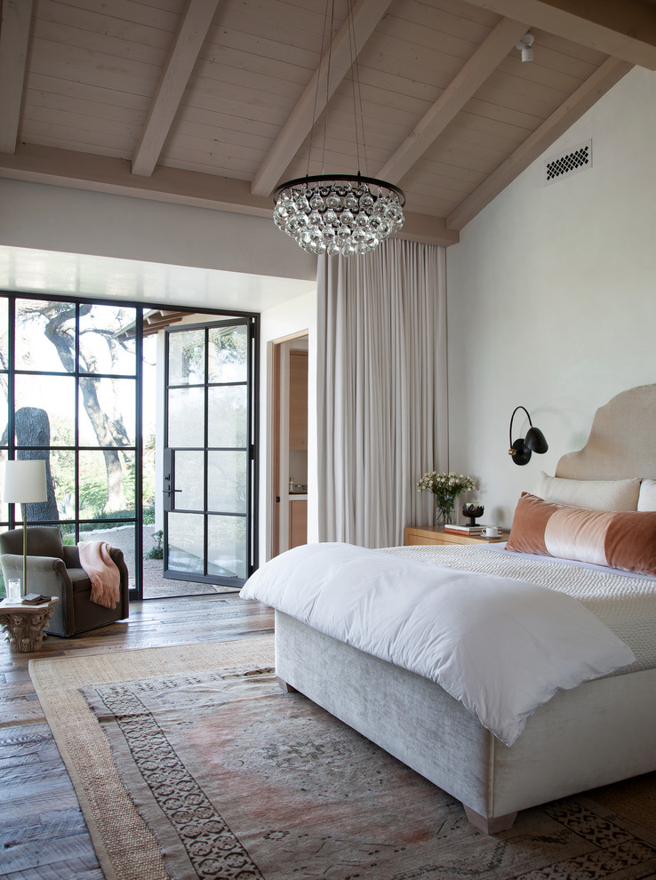 This is an example of a mediterranean bedroom in Austin with white walls, dark hardwood flooring and feature lighting.