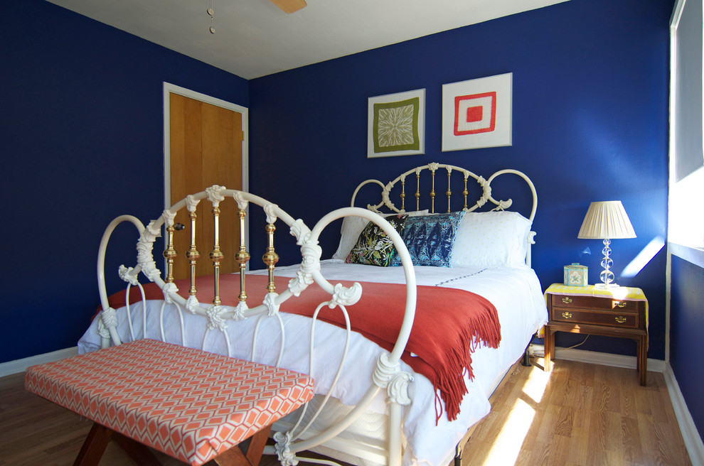 Immagine di una camera da letto boho chic con pareti blu e pavimento in legno massello medio