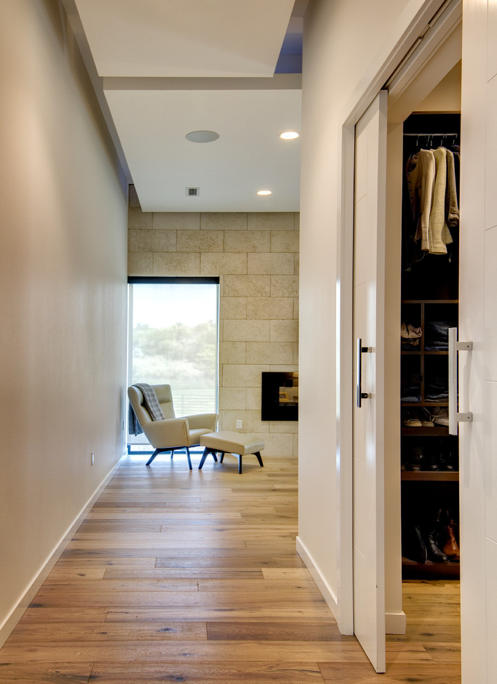На фото: хозяйская спальня среднего размера в стиле модернизм с белыми стенами, паркетным полом среднего тона, горизонтальным камином, фасадом камина из камня и коричневым полом