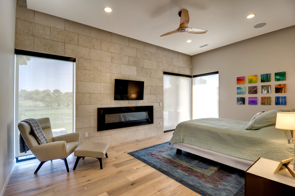 Mittelgroßes Modernes Hauptschlafzimmer mit weißer Wandfarbe, braunem Holzboden, Gaskamin, Kaminumrandung aus Stein und braunem Boden in Seattle