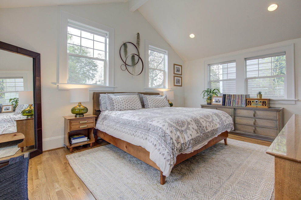 Modelo de dormitorio principal vintage de tamaño medio sin chimenea con paredes blancas, suelo de madera en tonos medios y suelo marrón