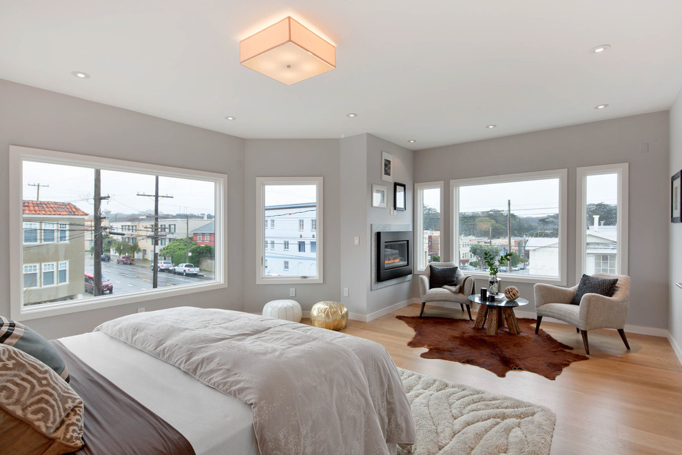 Example of a transitional light wood floor bedroom design in San Francisco with gray walls and a standard fireplace