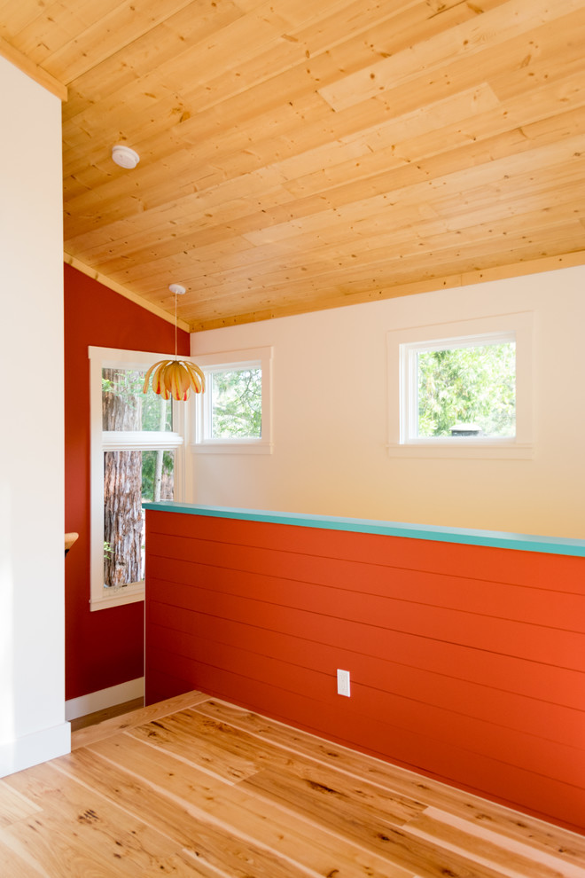 Aménagement d'une chambre parentale contemporaine de taille moyenne avec un mur orange, parquet clair, aucune cheminée et un sol marron.
