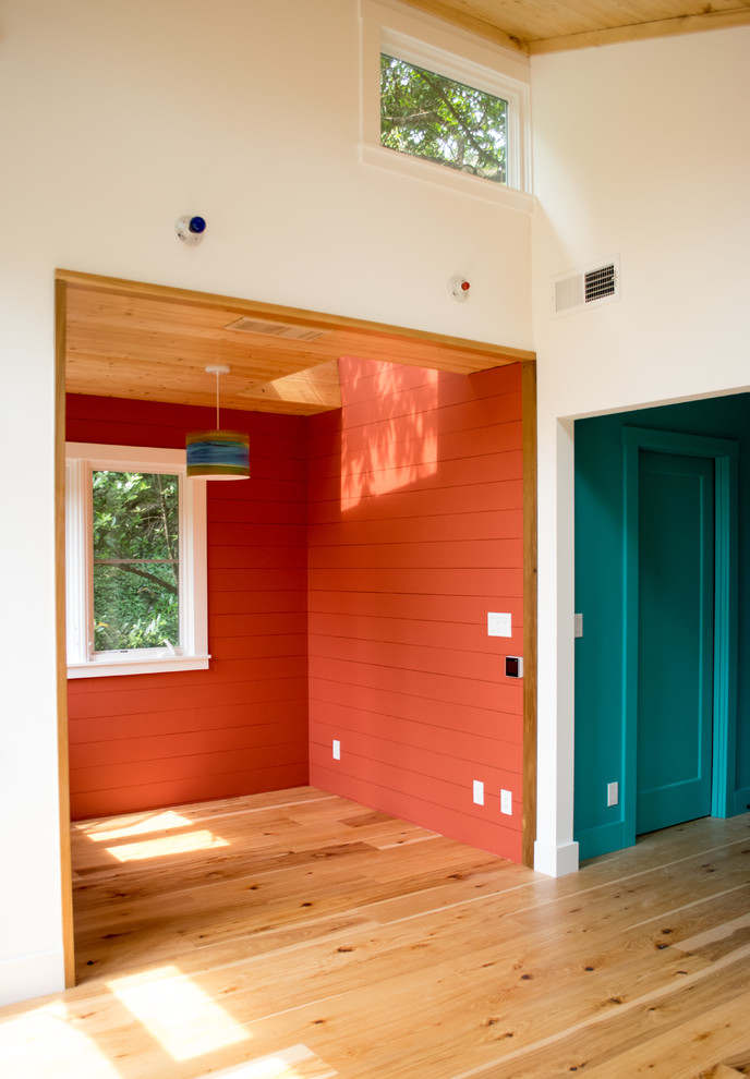 Inspiration pour une chambre parentale design de taille moyenne avec un mur orange, parquet clair, aucune cheminée et un sol marron.