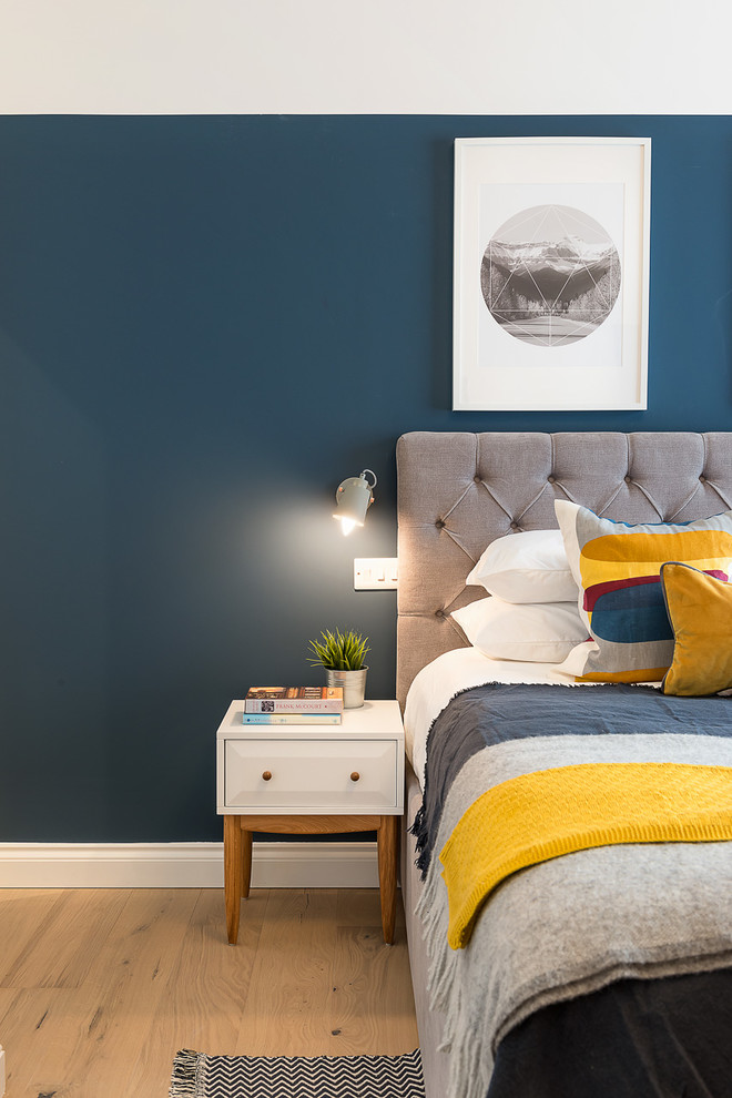 Imagen de dormitorio principal contemporáneo de tamaño medio sin chimenea con paredes azules, suelo de madera clara y suelo marrón
