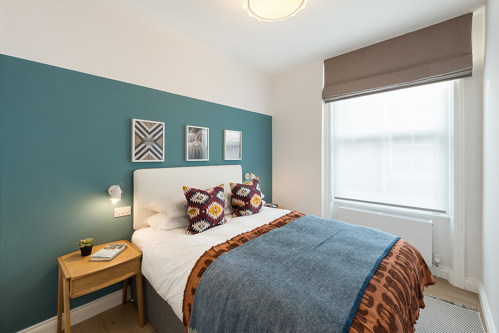 Foto de habitación de invitados actual de tamaño medio sin chimenea con paredes verdes, suelo de madera clara y suelo marrón