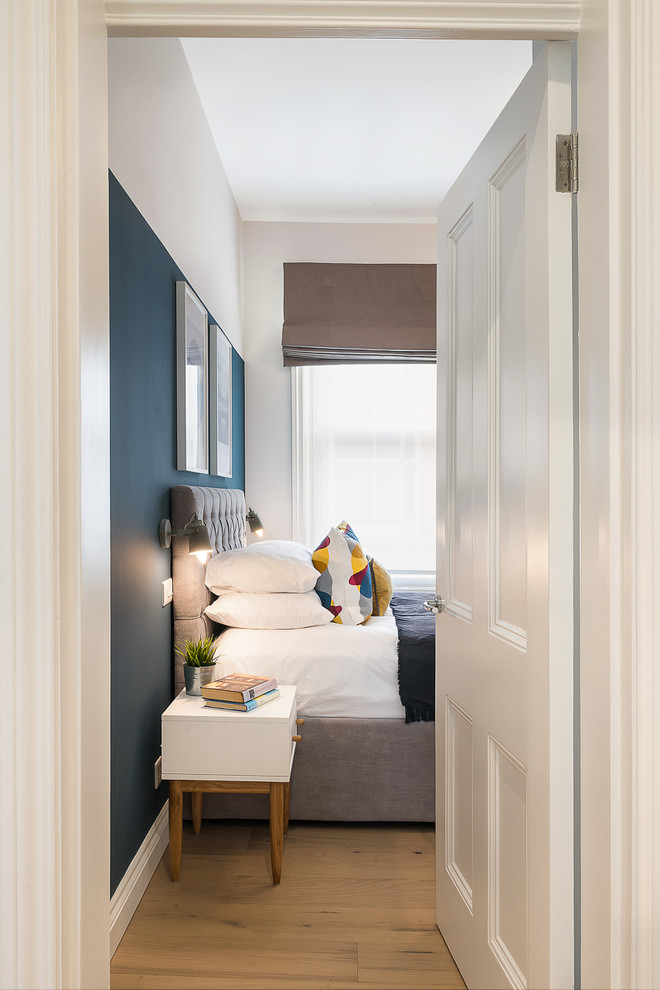 Ejemplo de dormitorio principal actual de tamaño medio sin chimenea con paredes azules, suelo de madera clara y suelo marrón