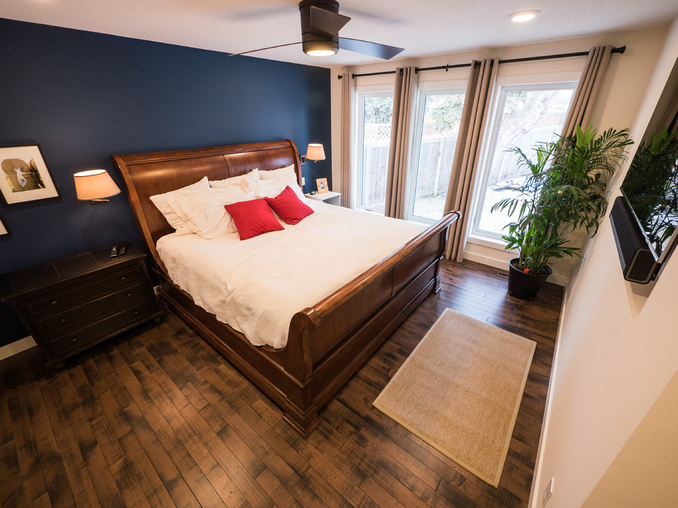 Mittelgroßes Klassisches Hauptschlafzimmer ohne Kamin mit dunklem Holzboden, braunem Boden und blauer Wandfarbe in Edmonton