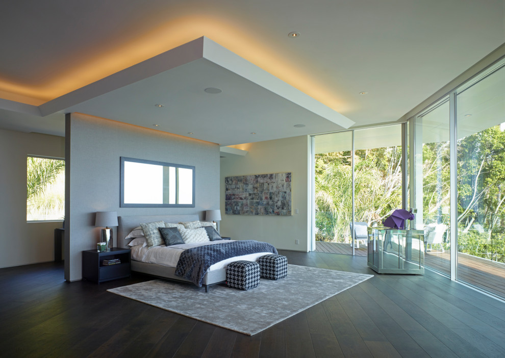 Geräumiges Modernes Hauptschlafzimmer mit weißer Wandfarbe, dunklem Holzboden, Gaskamin, Kaminumrandung aus Stein und braunem Boden in Los Angeles