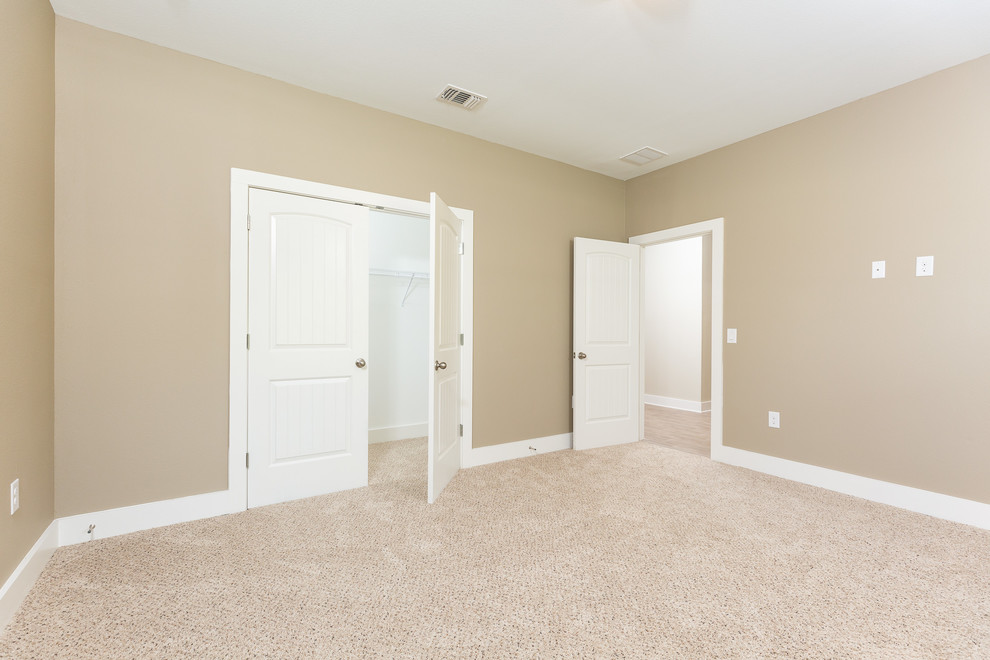 Medium sized traditional guest bedroom in Miami with beige walls, carpet and beige floors.
