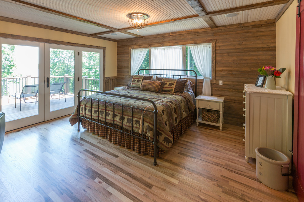 Imagen de dormitorio principal rural de tamaño medio con paredes multicolor, suelo de madera clara, todas las chimeneas, marco de chimenea de piedra y suelo multicolor